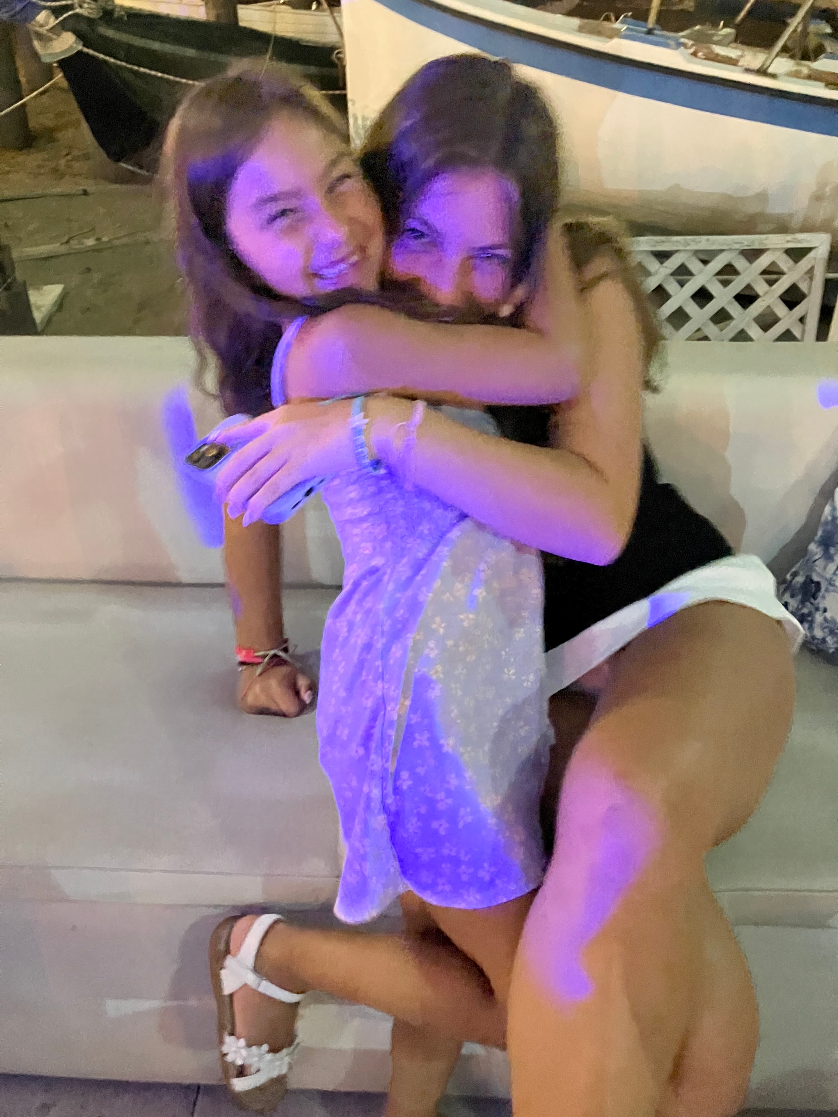 Two girls hugging under purple lights
