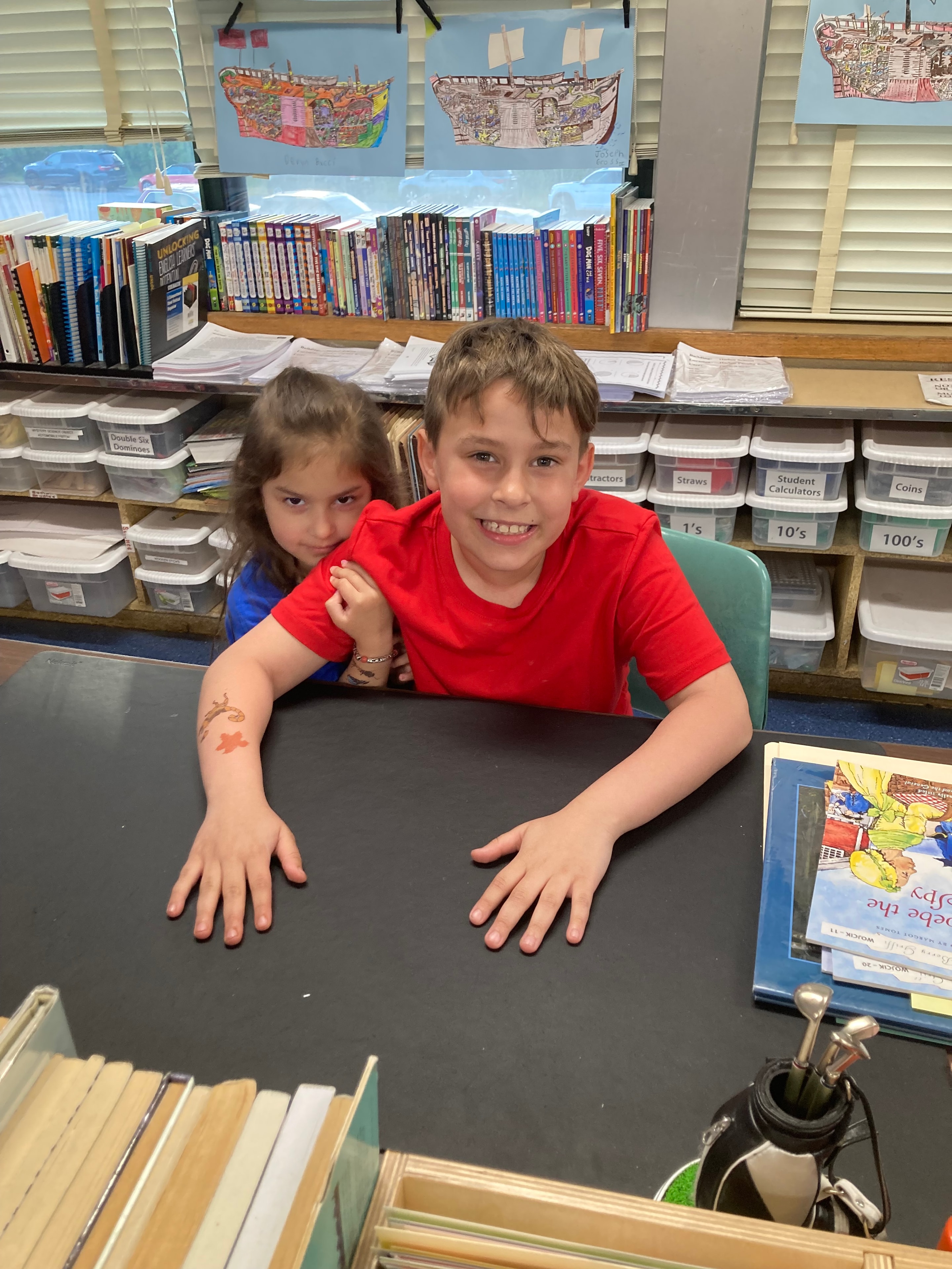 Two kids smiling together in a classroom